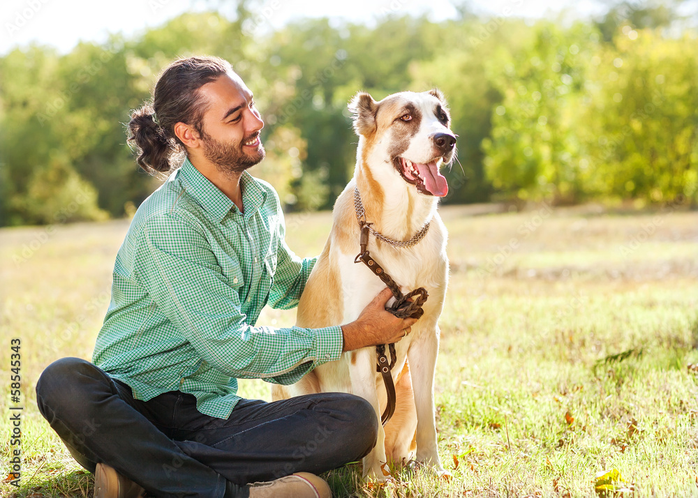 Man and central Asian shepherd walk in the park. Man and central Asian shepherd walk in the park.