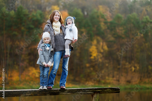 Two little sisters and their mom in autumn park