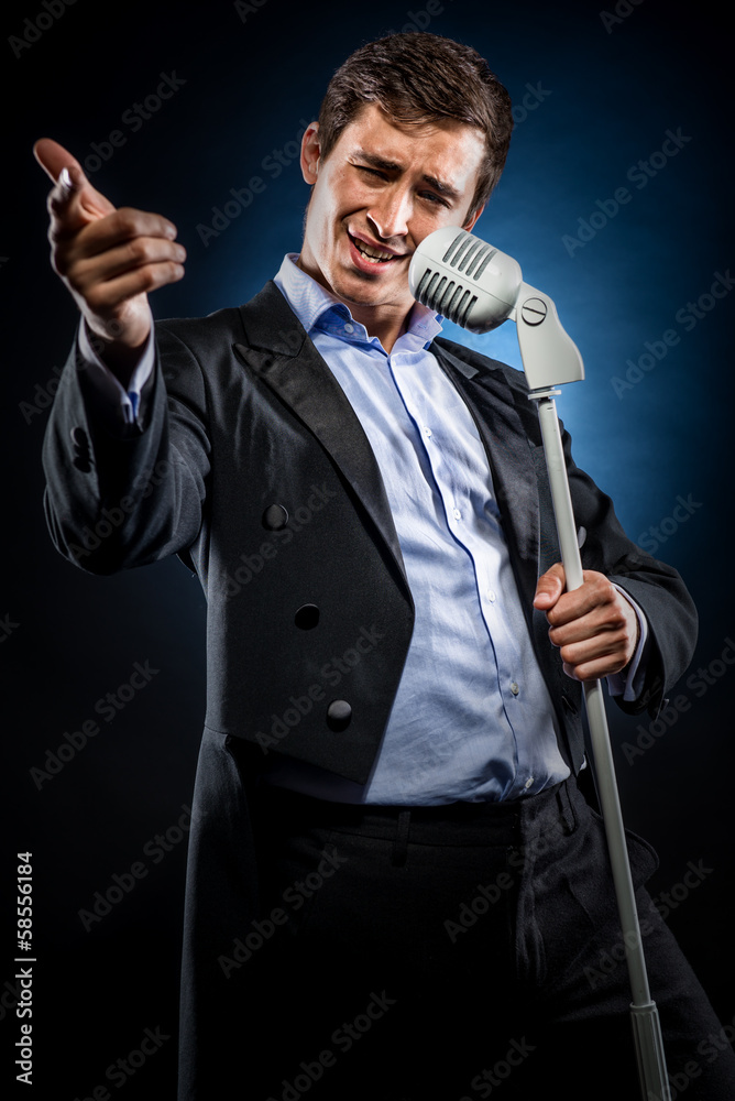 Man in elegant black jacket and blue shirt singing