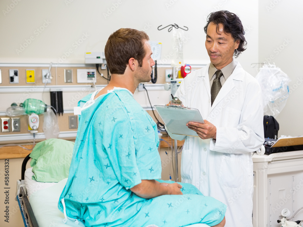 Doctor Examining Patient's Report In Hospital Doctor Examining Patient's Report In Hospital