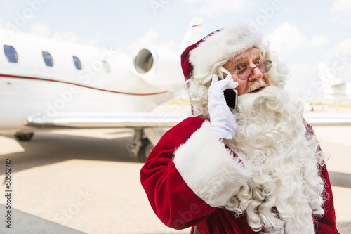 Surprised Santa Using Mobile Phone Against Private Jet