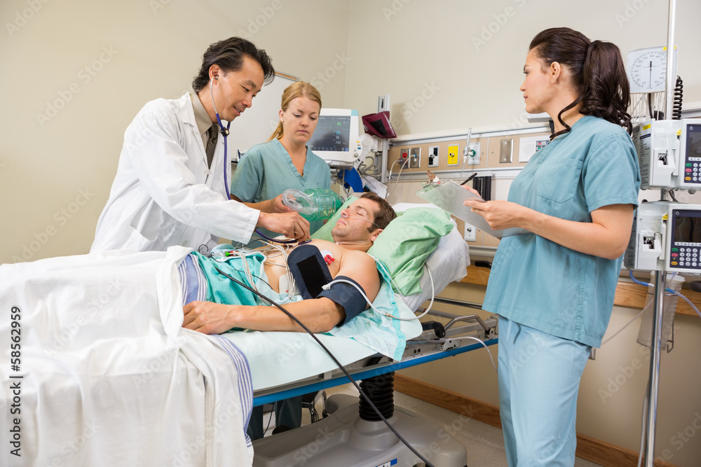 Nurses And Doctor Examining Male Patient