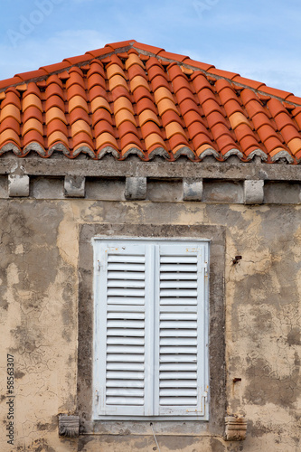 Building with orange roof tiles and wodden shuttered window