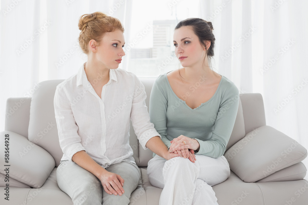 Woman consoling female friend while sitting on sofa Woman consoling female friend while sitting on sofa