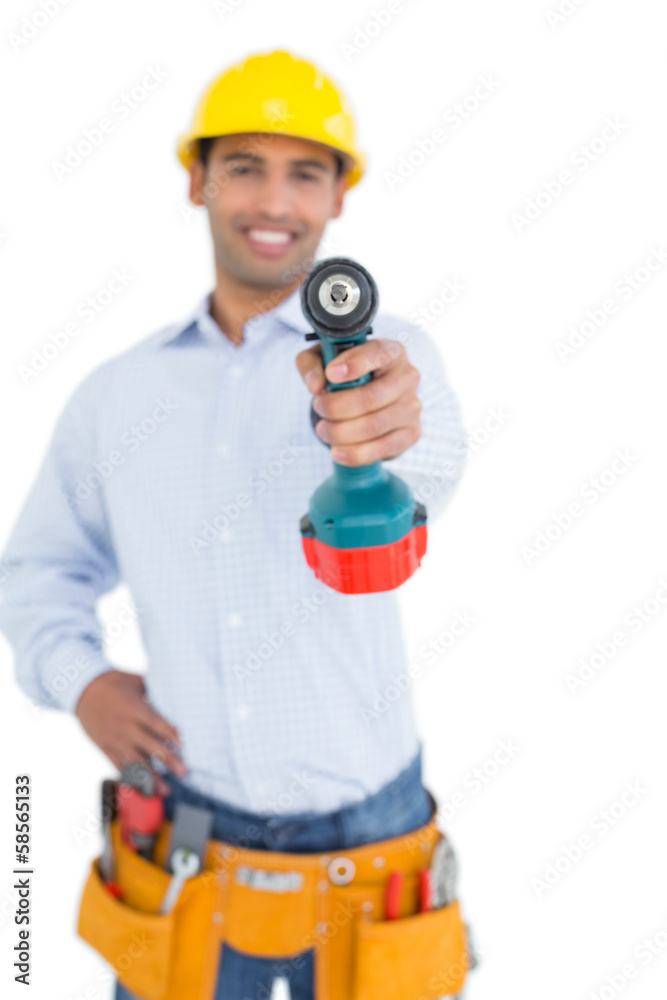 Smiling handsome young handyman holding out drill Smiling handsome young handyman holding out drill
