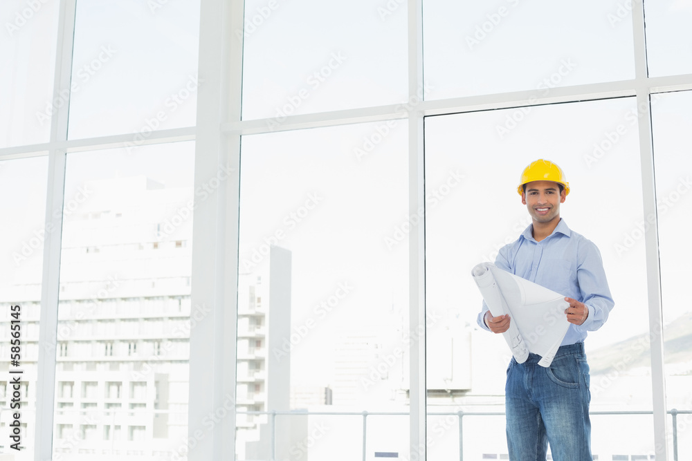 Young architect in yellow hard hat with blueprint in office Young architect in yellow hard hat with blueprint in office