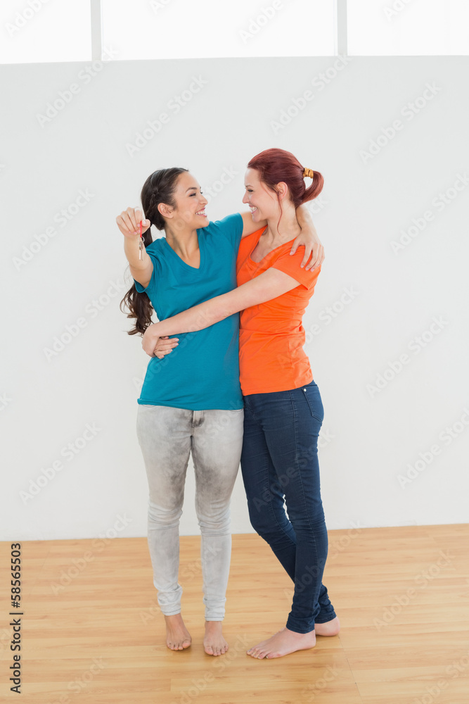 Woman embracing her friend with keys in a new house Woman embracing her friend with keys in a new house