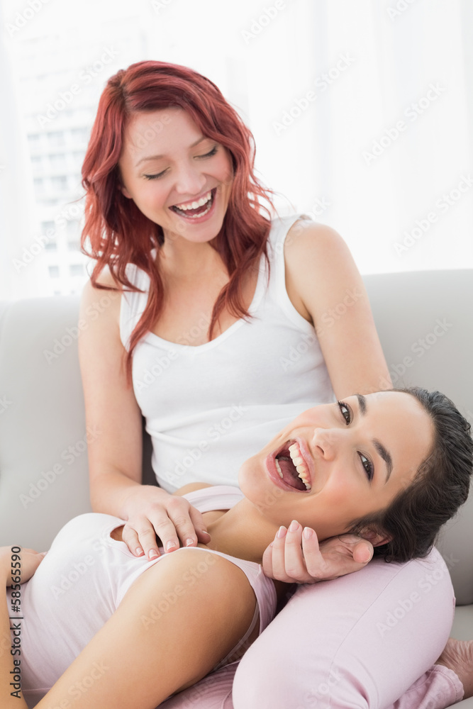 Cheerful young female resting on friend's lap in living room Cheerful young female resting on friend's lap in living room