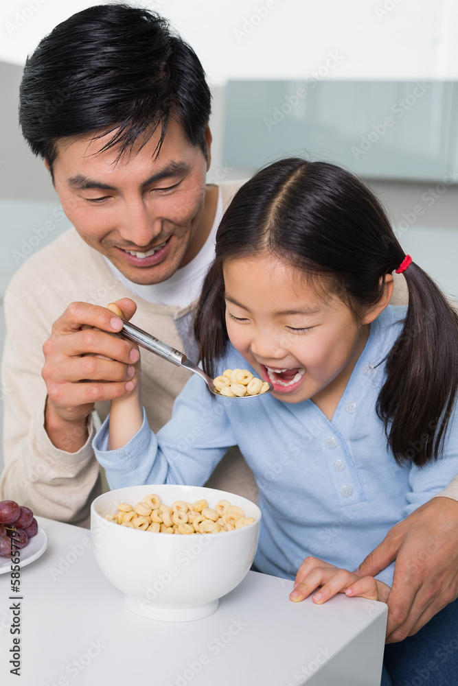 Father with young daughter having cereals in kitchen Father with young daughter having cereals in kitchen