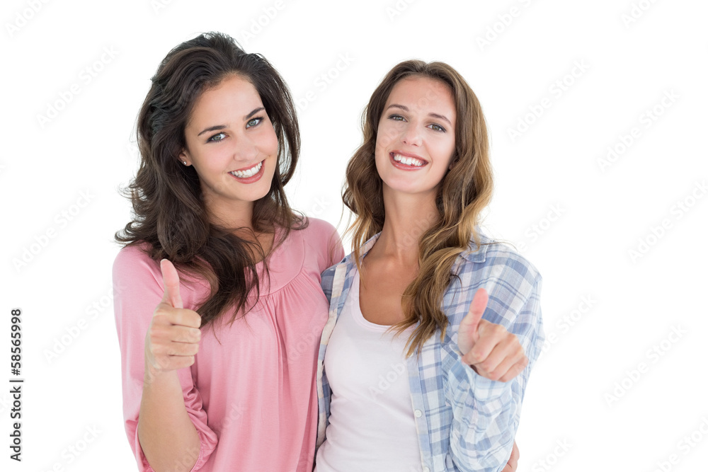 Portrait of two young female friends gesturing thumbs up Portrait of two young female friends gesturing thumbs up