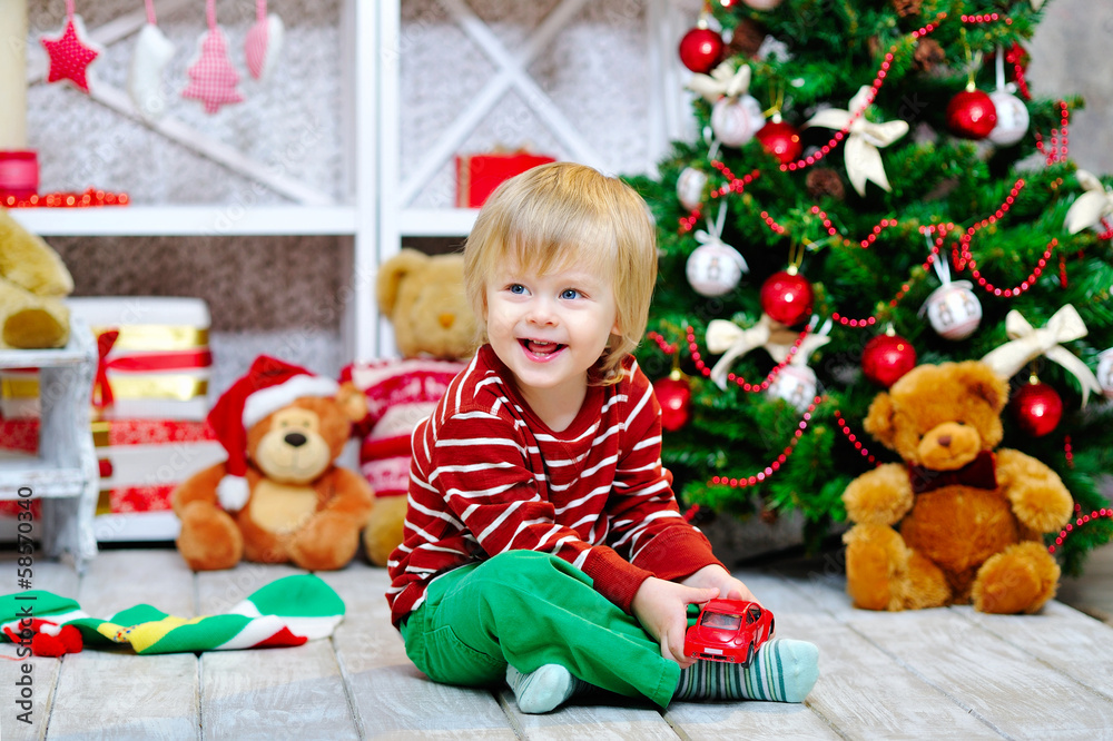 Cheerful little boy playing with his red toy car Cheerful little boy playing with his red toy car