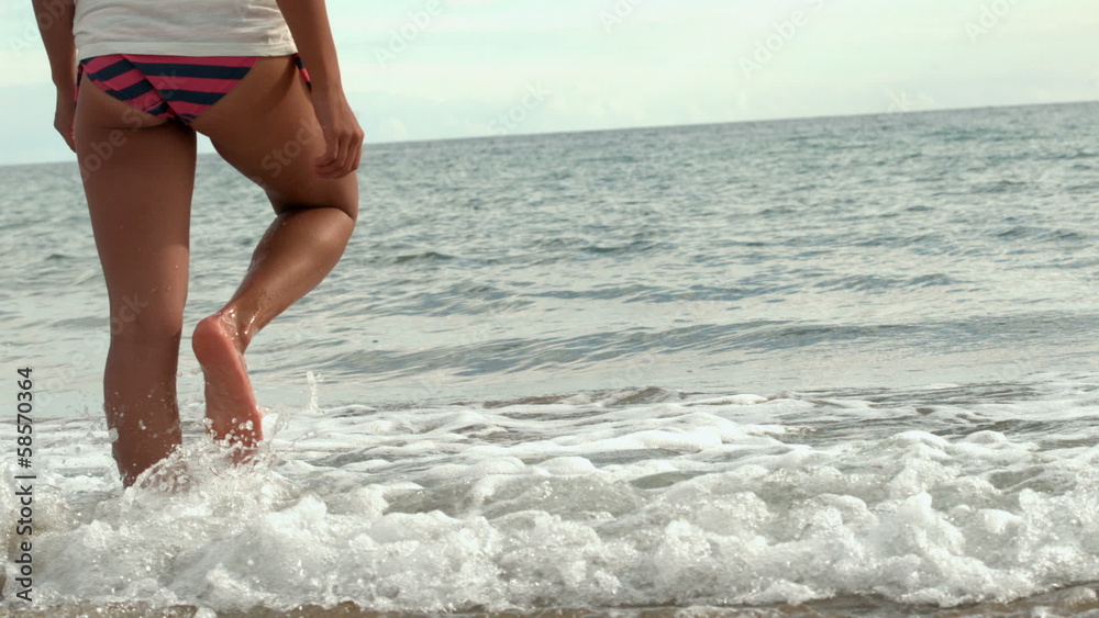 Female legs walking into the water Female legs walking into the water