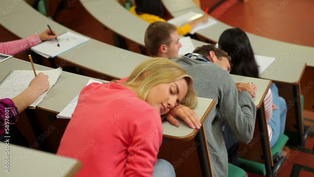Student asleep at desk in lecture hall Student asleep at desk in lecture hall
