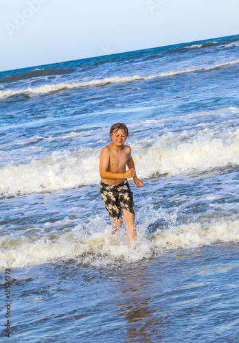 young boy running through the water at the beach