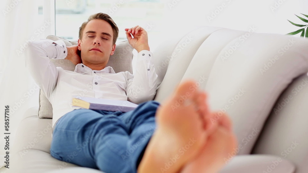 Attractive young man lying on couch while sleeping