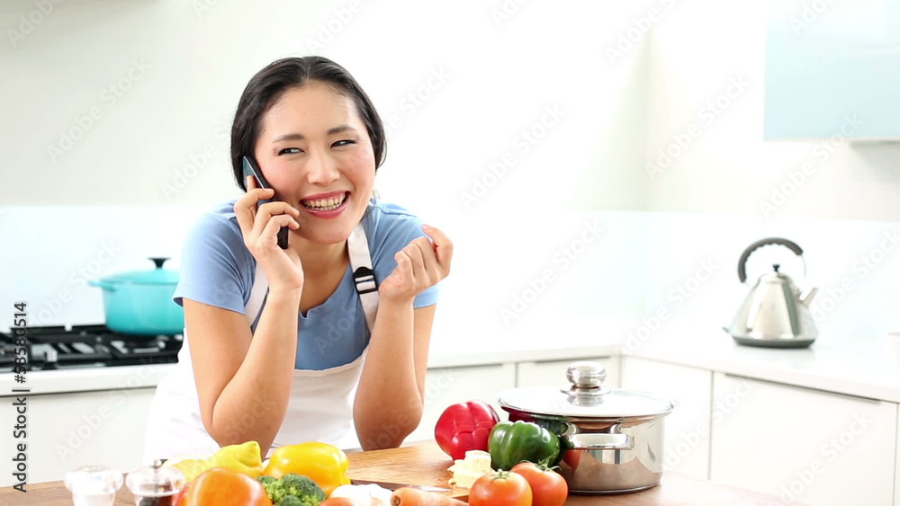 Happy woman preparing dinner and talking on the phone Happy woman preparing dinner and talking on the phone
