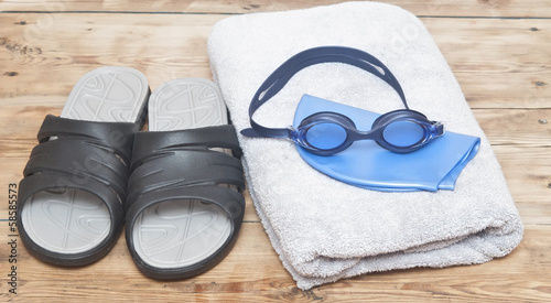 glasses for swimming and towel on wooden background