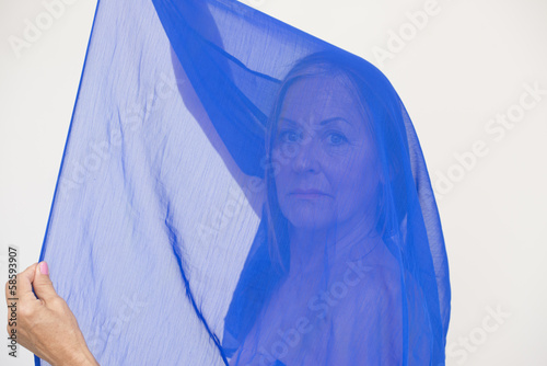 Mysterious serious lady behind blue cloth