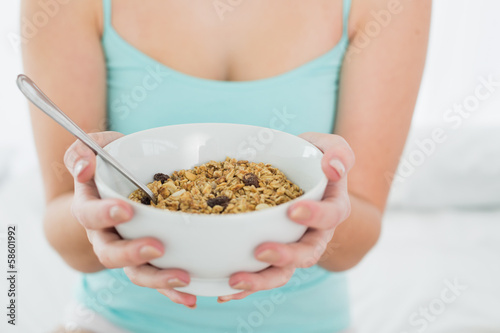 Mid section of a female with a bowl of cereal in bed
