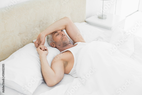 Mature man sleeping in bed at home