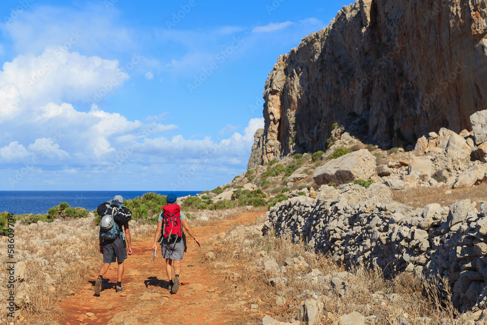Two unidentified men walk the path to the rocks in Sicily
