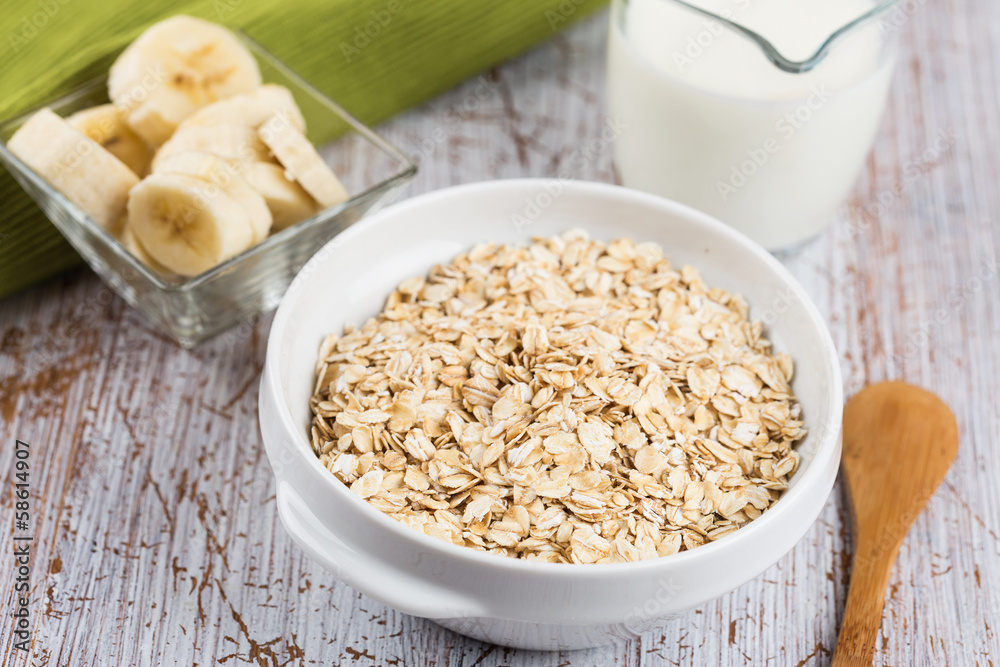 Oat flakes in bowl with banana and milk Oat flakes in bowl with banana and milk