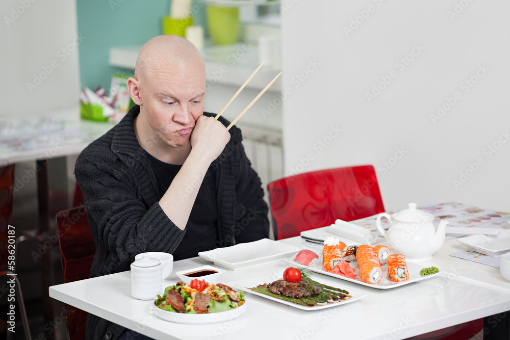 Man with surprised face eats sushi in cafe Man with surprised face eats sushi in cafe