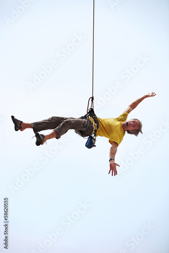 Happy rock climber hanging on rope
