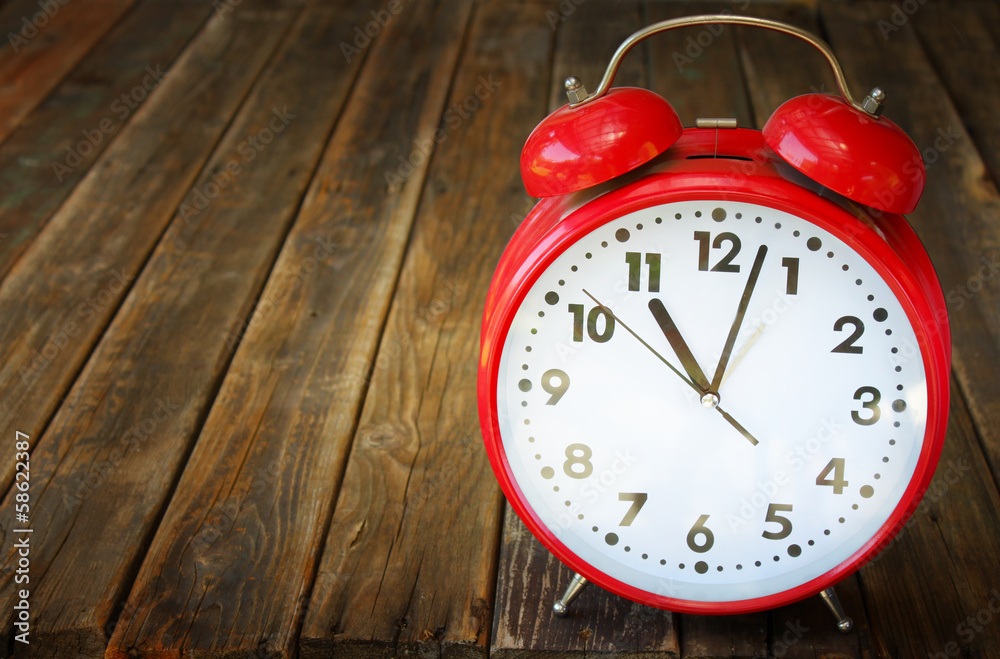 Naklejka premium red vintage clock on wooden table