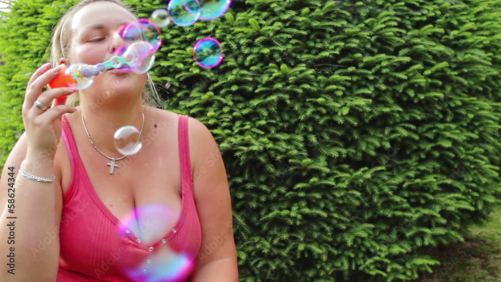 Busty woman in garden blowing bubbles Busty woman in garden blowing bubbles