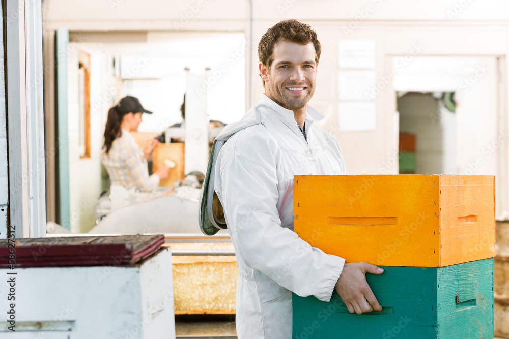 Male Beekeeper Carrying Stack Of Honeycomb Crates