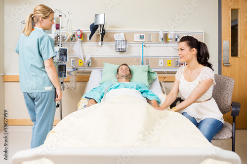 Woman Holding Patient s Hand While Looking At Nurse