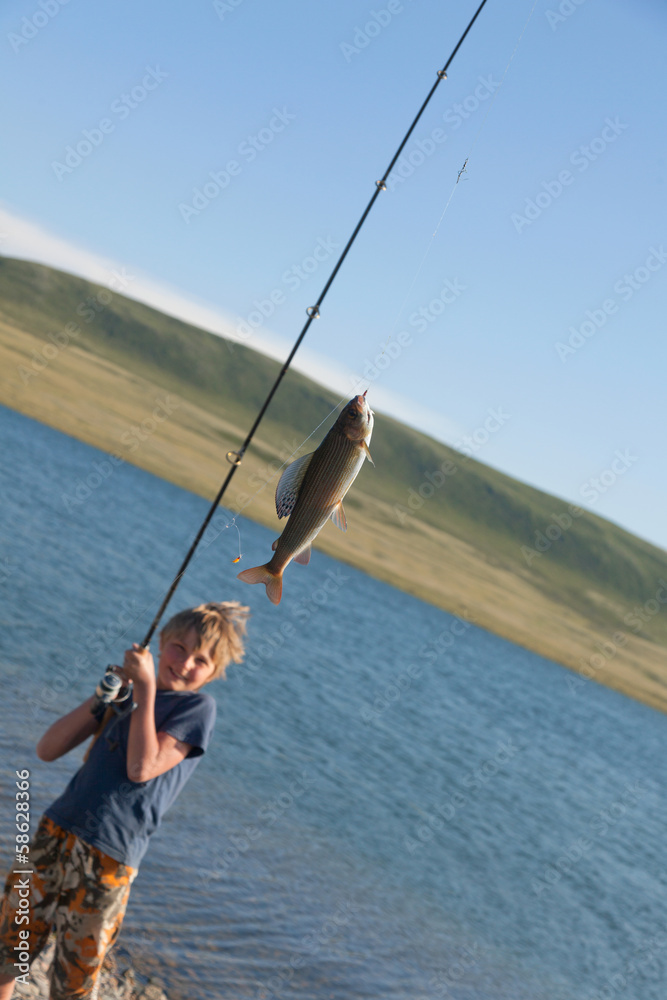 The boy with a spinning catch grayling The boy with a spinning catch grayling