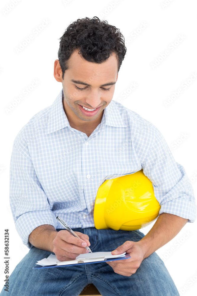Handyman with yellow hard hat writing in clipboard Handyman with yellow hard hat writing in clipboard