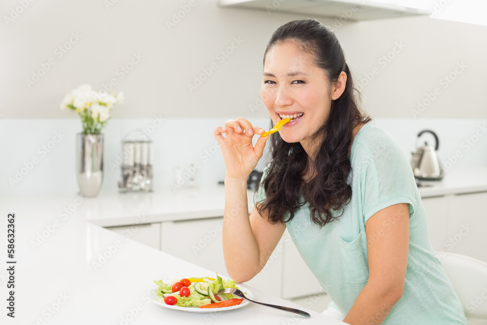 Portrait of a young woman eating salad in kitchen Portrait of a young woman eating salad in kitchen