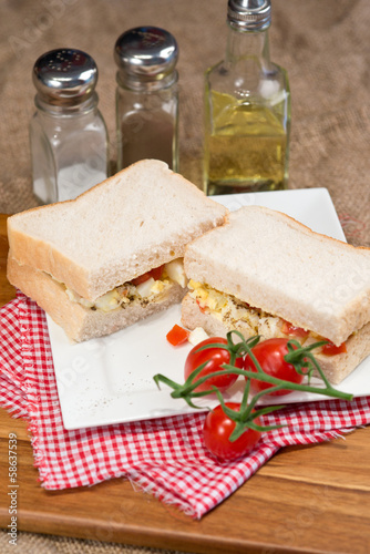 Fresh egg and tomato on white sandwich in rustic kitchen setting