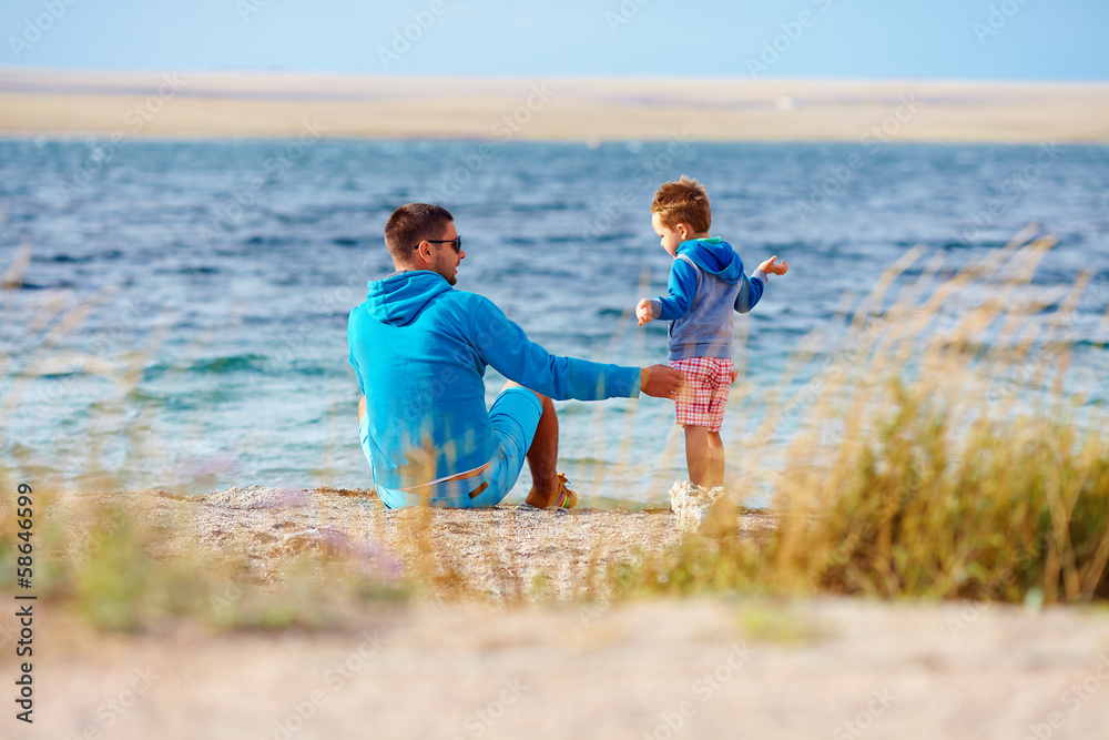 father and son together on lake coast father and son together on lake coast