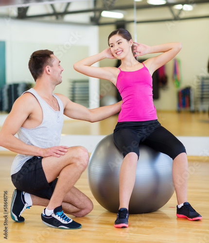 male trainer with woman doing crunches on the ball
