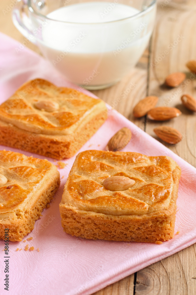 Almond biscuits on pink tablecloth with a cup of milk Almond biscuits on pink tablecloth with a cup of milk