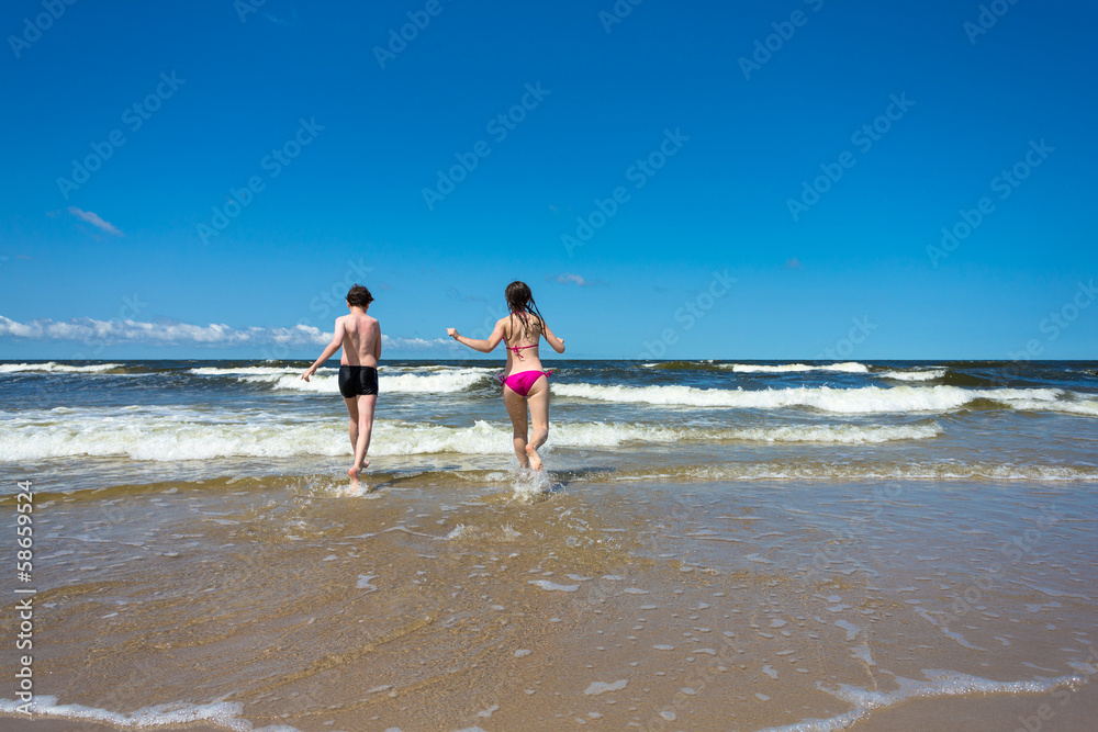 Teenage girl and boy running, jumping on beach Teenage girl and boy running, jumping on beach