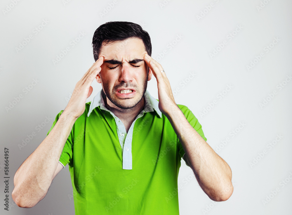Portrait of young man wearing green shirt having head pain Portrait of young man wearing green shirt having head pain