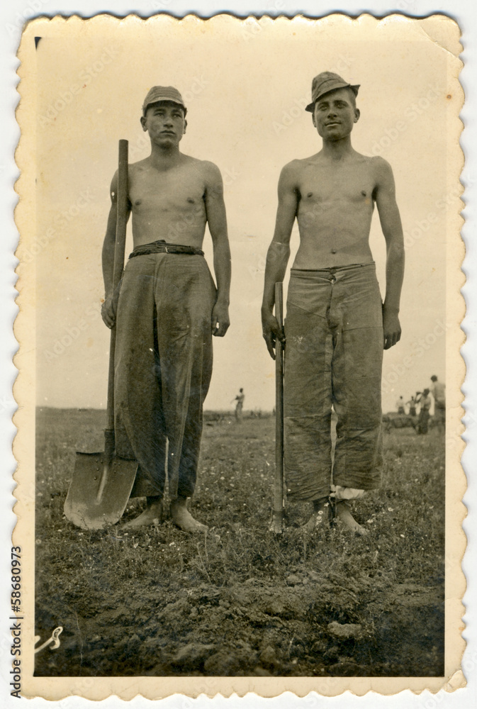 CIRCA 1940: Two young men (probably in military trousers)