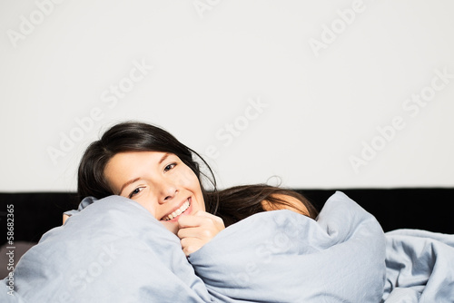 Laughing woman snuggling up in her bed