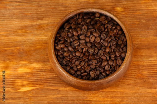 Coffee beans in wooden bowl on wooden background