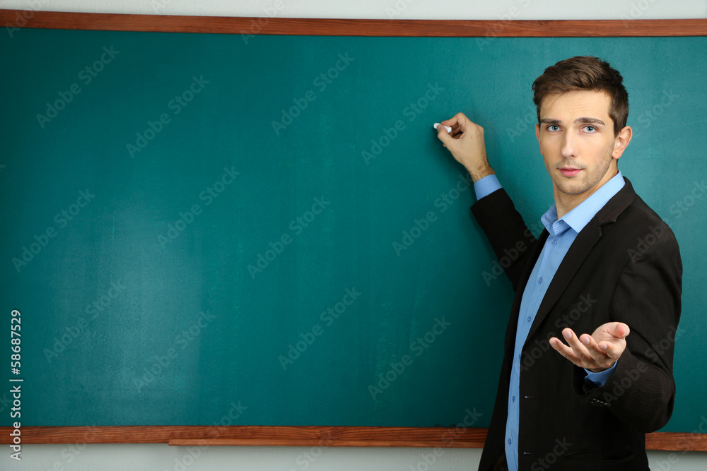 Young teacher near chalkboard in school classroom Young teacher near chalkboard in school classroom
