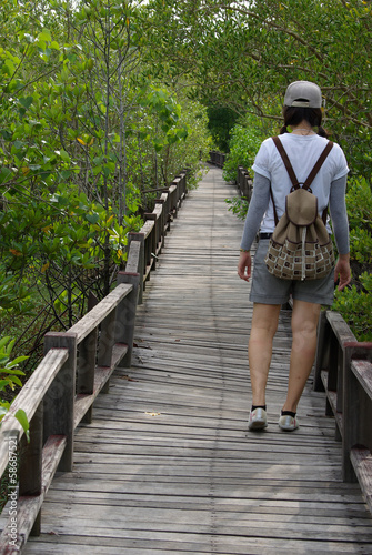 A girl walking away towards a forest on a wooden