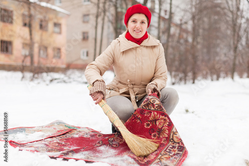 woman in red cap cleans carpet with snow