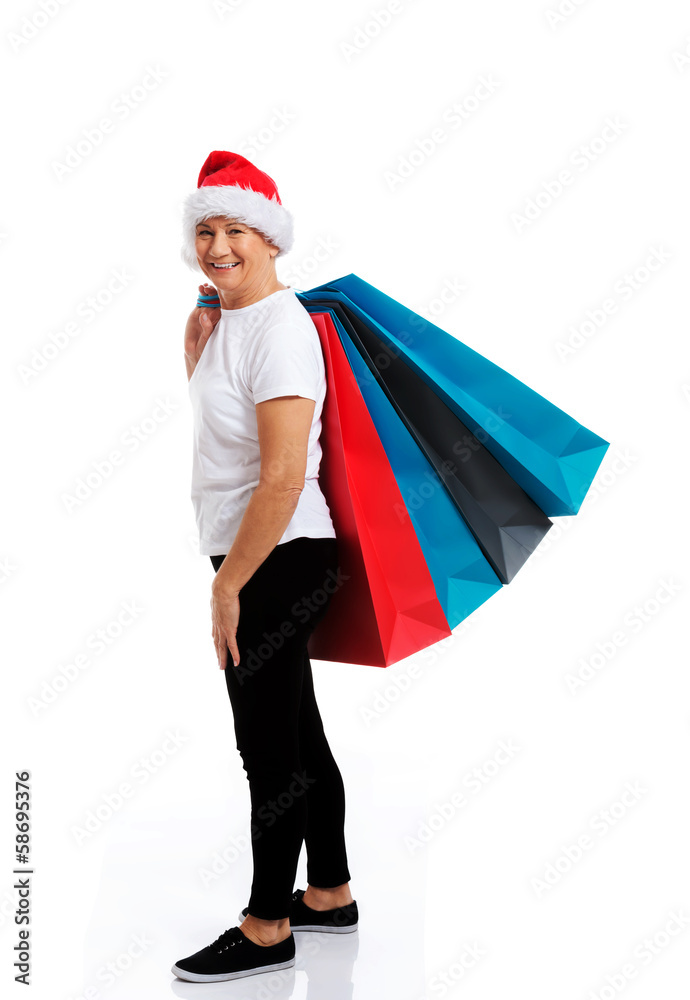 An old woman holding presents/bags in santa hat. An old woman holding presents/bags in santa hat.
