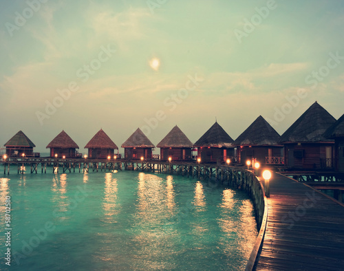 houses on piles on water at night in fool moon light,