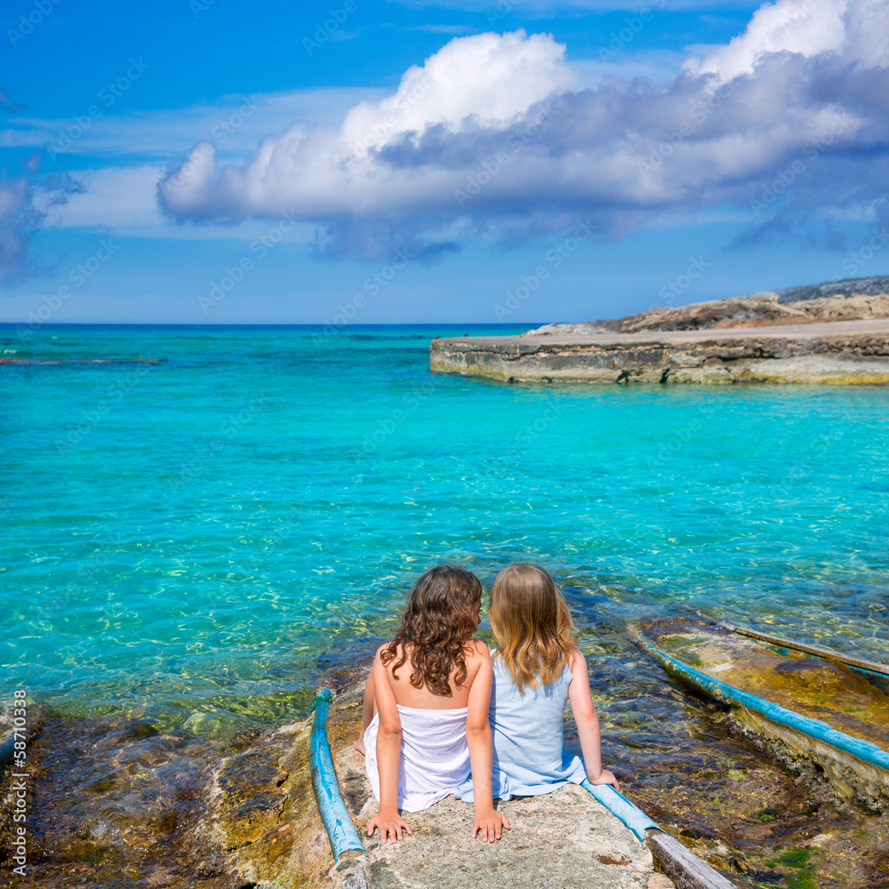 Blond and brunette kid girls sitting on beach port Blond and brunette kid girls sitting on beach port